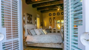 A bedroom with a bed, a nightstand, and a window with blinds.