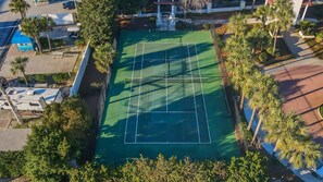 An aerial view of a tennis court surrounded by palm trees and a pool. - 9 Rue Martine in Miramar Beach (Miramar Beach)