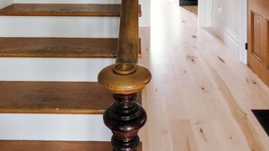 A wooden staircase with a dark balustrade leading to a kitchen area. - SquirrelHaus PEC Summ (Prince Edward)