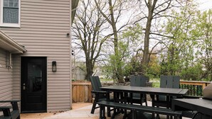 A deck with a table and chairs, a black door, and a wooden fence. - SquirrelHaus PEC Summ (Prince Edward)