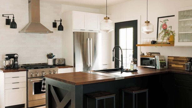 A modern kitchen with stainless steel appliances, a wooden island, and pendant lighting. - SquirrelHaus PEC Summ (Prince Edward)