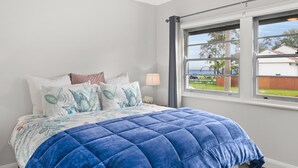 A bedroom with a bed, a ceiling fan, a window, and a view of the outside. - Cottage by the Lake, 1 bedroom full size house, full kitchen, 2 living areas.  (Long Jetty)