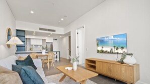 Una sala de estar moderna con un sofá, una mesa de centro y un cuadro de una playa.