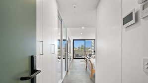 Un couloir d’hôtel moderne avec une porte en verre donnant sur un balcon d’où l’on peut admirer la vue.