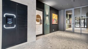 A modern lobby with a digital resident and courier service kiosk, a prominent 'LOOP' logo, and a large artwork of birds.
