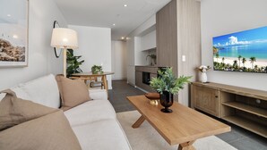 A modern living room with a sofa, a coffee table, a lamp, and a painting of a beach scene. - Bright & Cosy Studio in Prime Fremantle Location (North Fremantle)