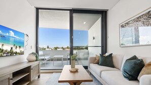 Un salon moderne avec un canapé, une table basse et un téléviseur fixé au mur.