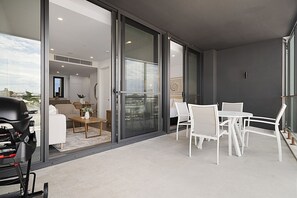 A modern balcony with a dining set and a grill.
