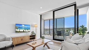 A modern living room with a large TV, a wooden coffee table, and a sofa.