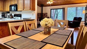 Un comedor con mesa de madera, sillas y un florero.