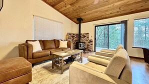 Una sala de estar acogedora con chimenea, sofás de cuero y techo de madera.