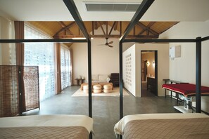 Ein Zimmer mit einem Bett, einem Deckenventilator, einer Holzbalkendecke, einem großen Fenster und einer Wand mit Kalligraphie.