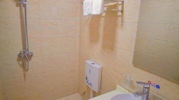 A bathroom with a shower, a sink, a mirror, and a towel rack.