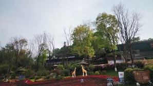 A garden with giraffe statues, a pagoda-style building, and a signboard. - Yi Xian Ju Inn (Ya'an)
