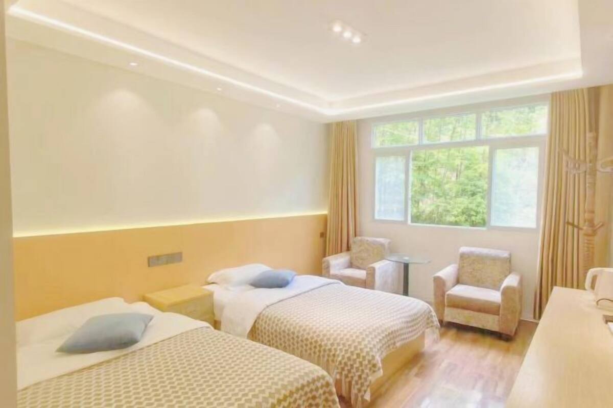Quarto de hotel com duas camas, uma mesinha e uma cadeira.