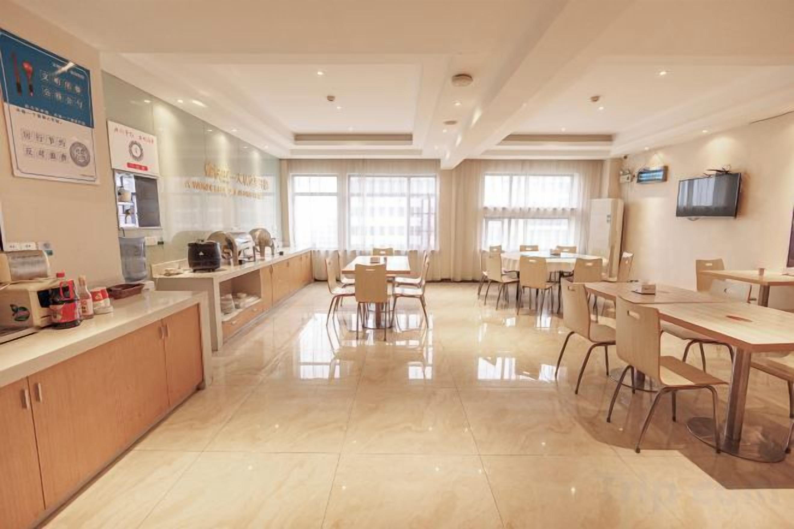 Een restaurantruimte in een hotel met een lange toonbank, meerdere tafels en stoelen.
