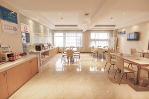 A hotel dining area with a long counter, multiple tables, and chairs. - City Zhixin Boutique Hotel (Infrastructure Camp Central Hospital) (Xiangtan)