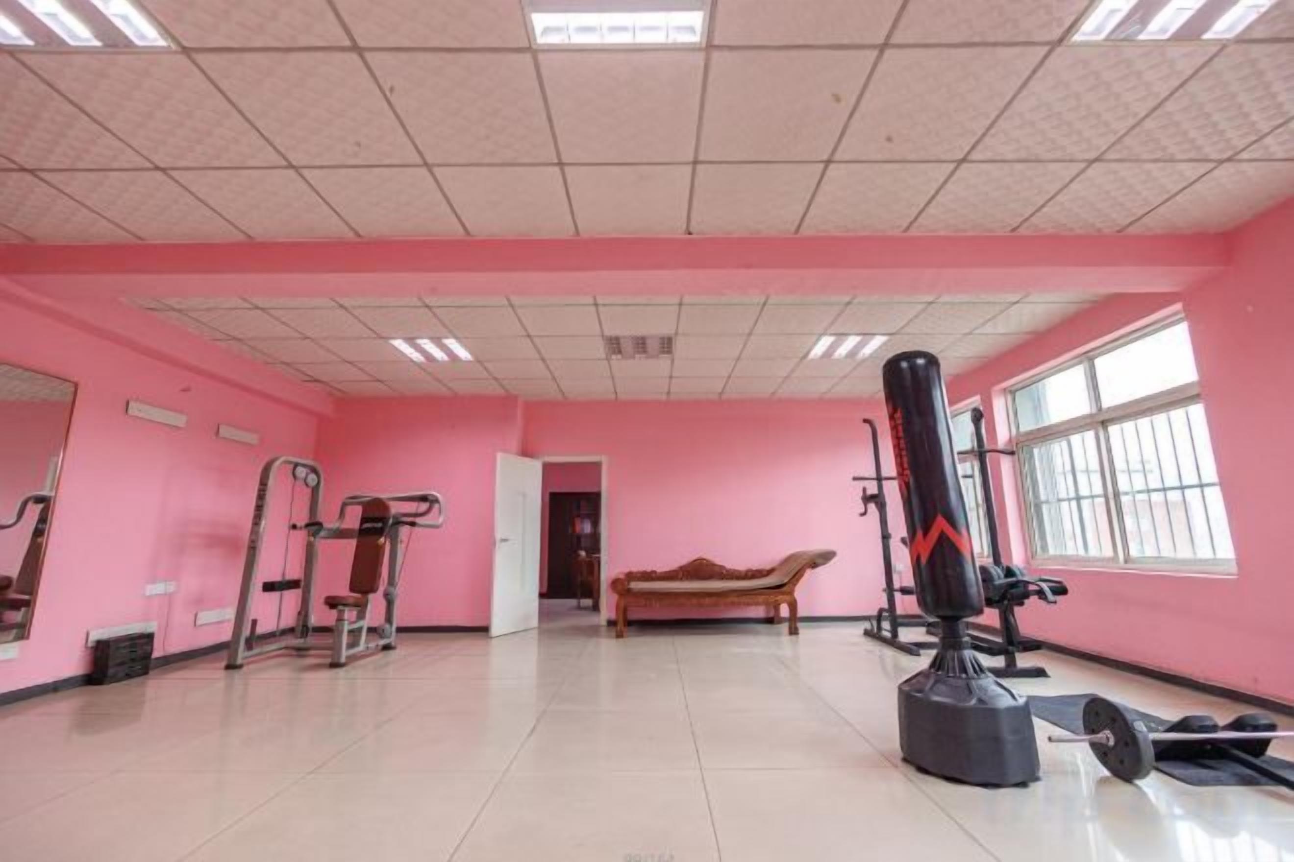 Un gimnasio con equipamiento de ejercicio, una banca y un saco de boxeo.