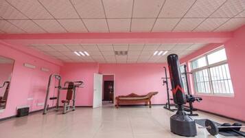 Un gimnasio con equipamiento de ejercicio, una banca y un saco de boxeo.