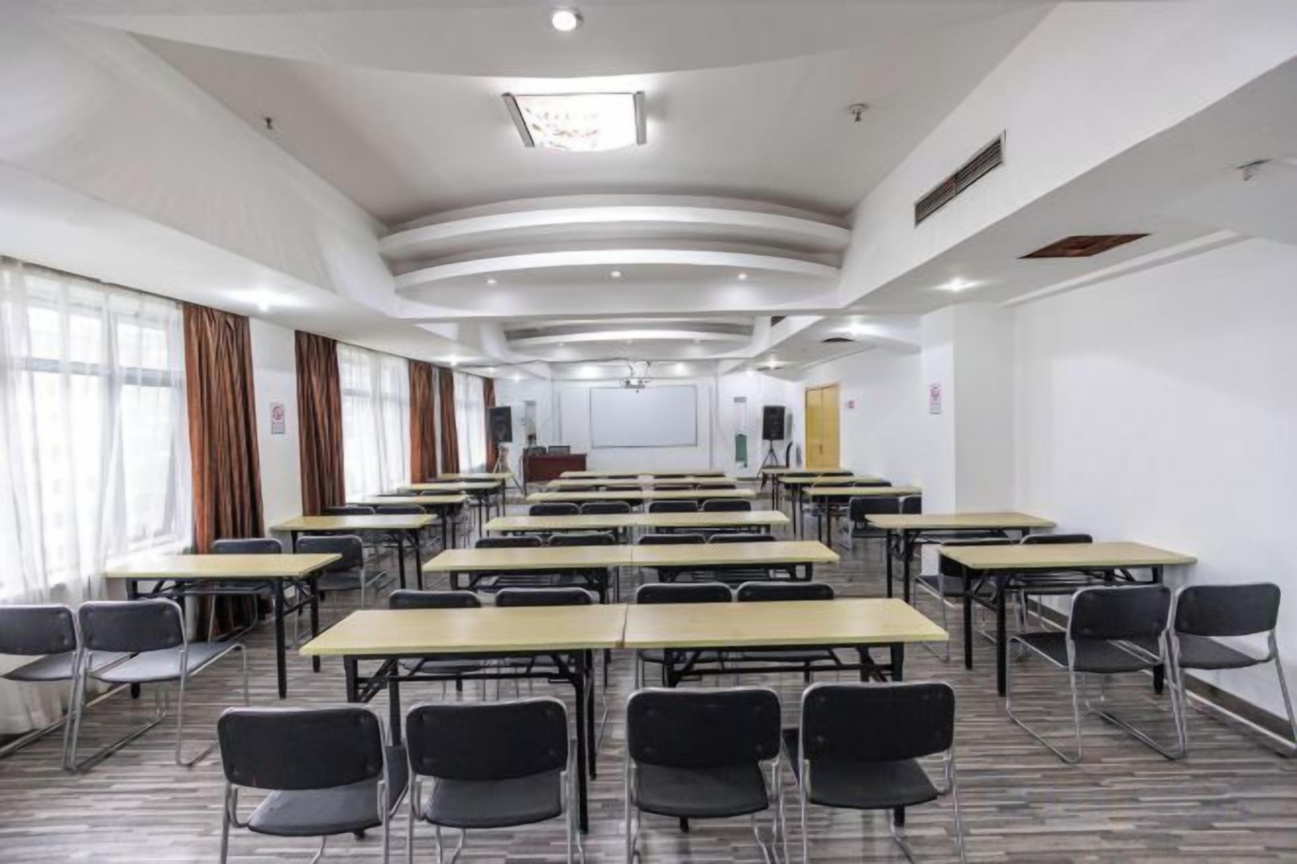A conference room with multiple tables and chairs, a projector screen, and a whiteboard.