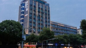 Un hotel de varios pisos con un diseño moderno, que destaca un logotipo en la fachada.