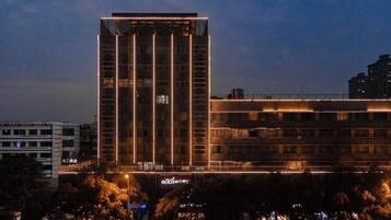 Een meerlaags hotel met een modern ontwerp, voorzien van een opvallende verticale lichtstrook op de gevel.