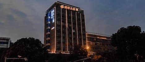 Edifício de vários andares com uma placa vertical chamativa na fachada, possivelmente indicando um hotel ou estabelecimento comercial.