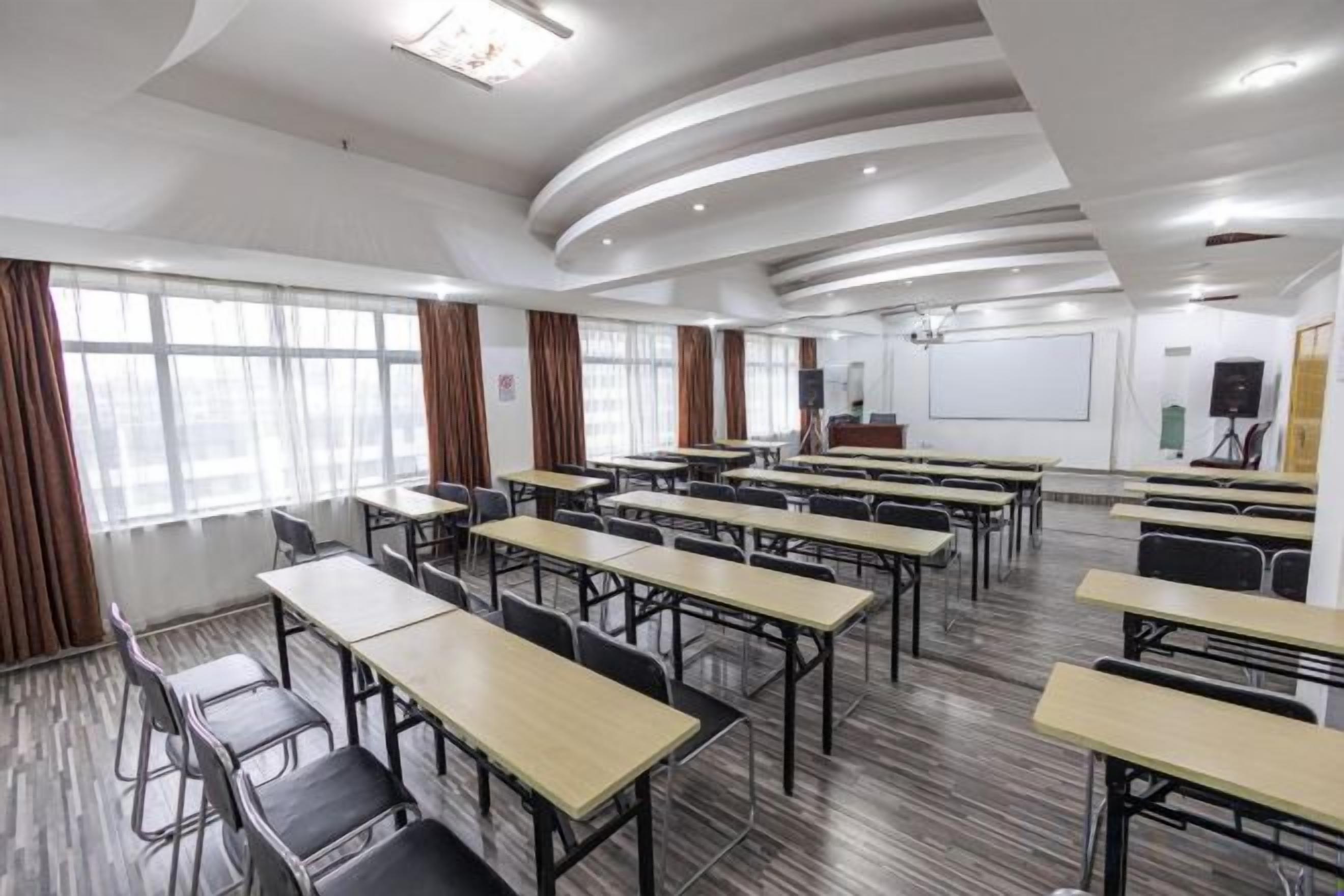 A conference room with multiple tables and chairs, a whiteboard, and a projector screen.