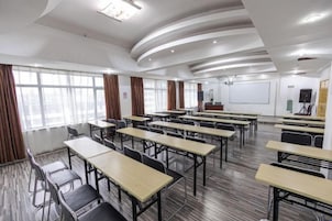 A conference room with multiple tables and chairs, a whiteboard, and a projector screen.