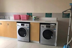 A laundry area with two washing machines and a counter with baskets. - City Zhixin Boutique Hotel (Infrastructure Camp Central Hospital) (Xiangtan)