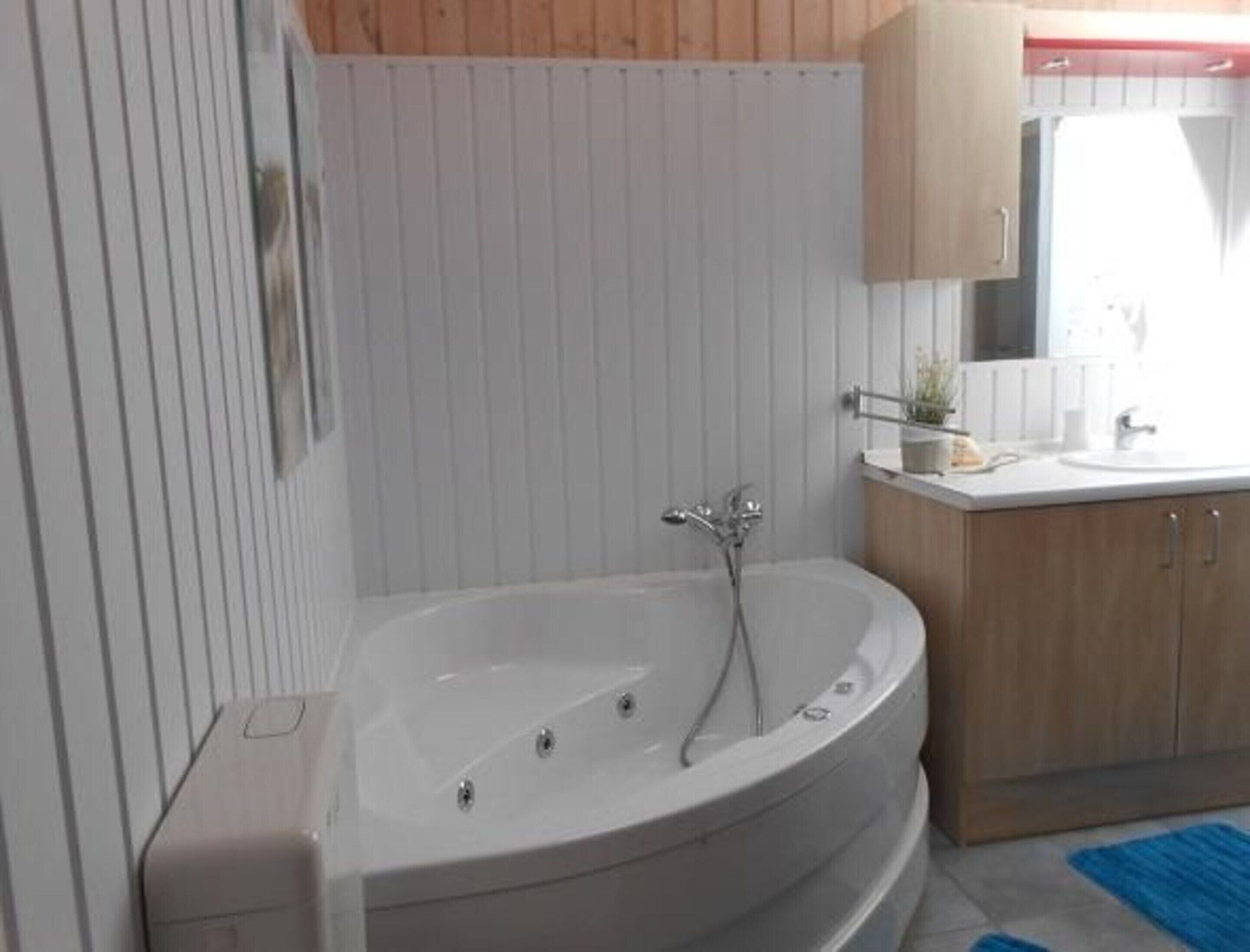 A bathroom with a freestanding bathtub, a sink, and wooden cabinets.