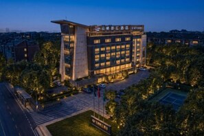 A multi-story building with a prominent entrance, a courtyard, and a tennis court. - Chengdu YunSHEY Hotel (Chengdu)