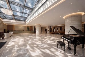 A spacious lobby with a grand piano, a reception desk, and a high ceiling with skylights. - Chengdu YunSHEY Hotel (Chengdu)