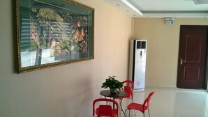 A room with a dining area featuring a table with chairs, a potted plant, and a large framed artwork on the wall. - Guxiangyi Hotel (Shanghai)
