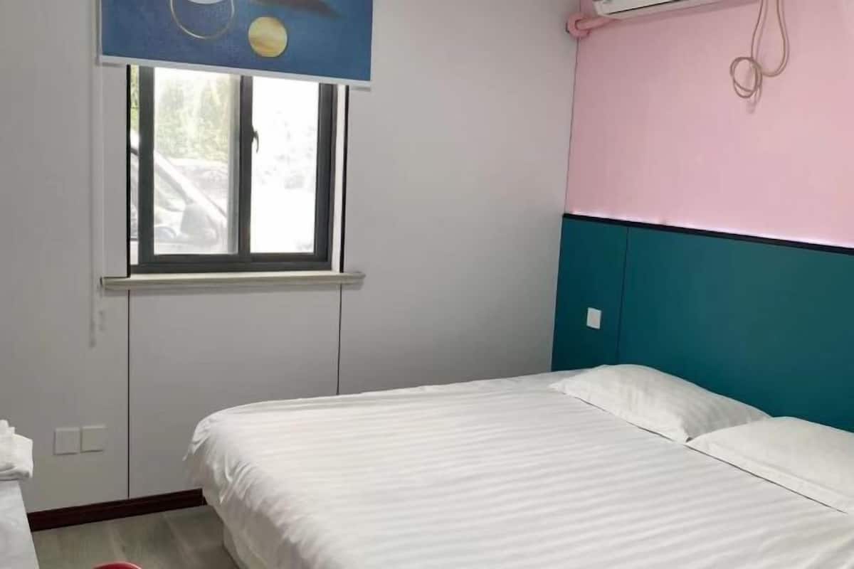 A bedroom with a bed, a window, and a wall-mounted air conditioning unit.