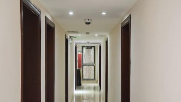 A corridor with a polished floor, dark wooden doors, and recessed lighting. - Guxiangyi Hotel (Shanghai)