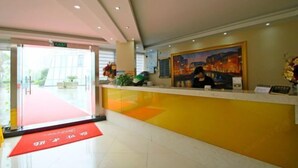 A hotel reception area with a red carpet leading to the entrance, a reception desk, and a painting on the wall. - Guxiangyi Hotel (Shanghai)