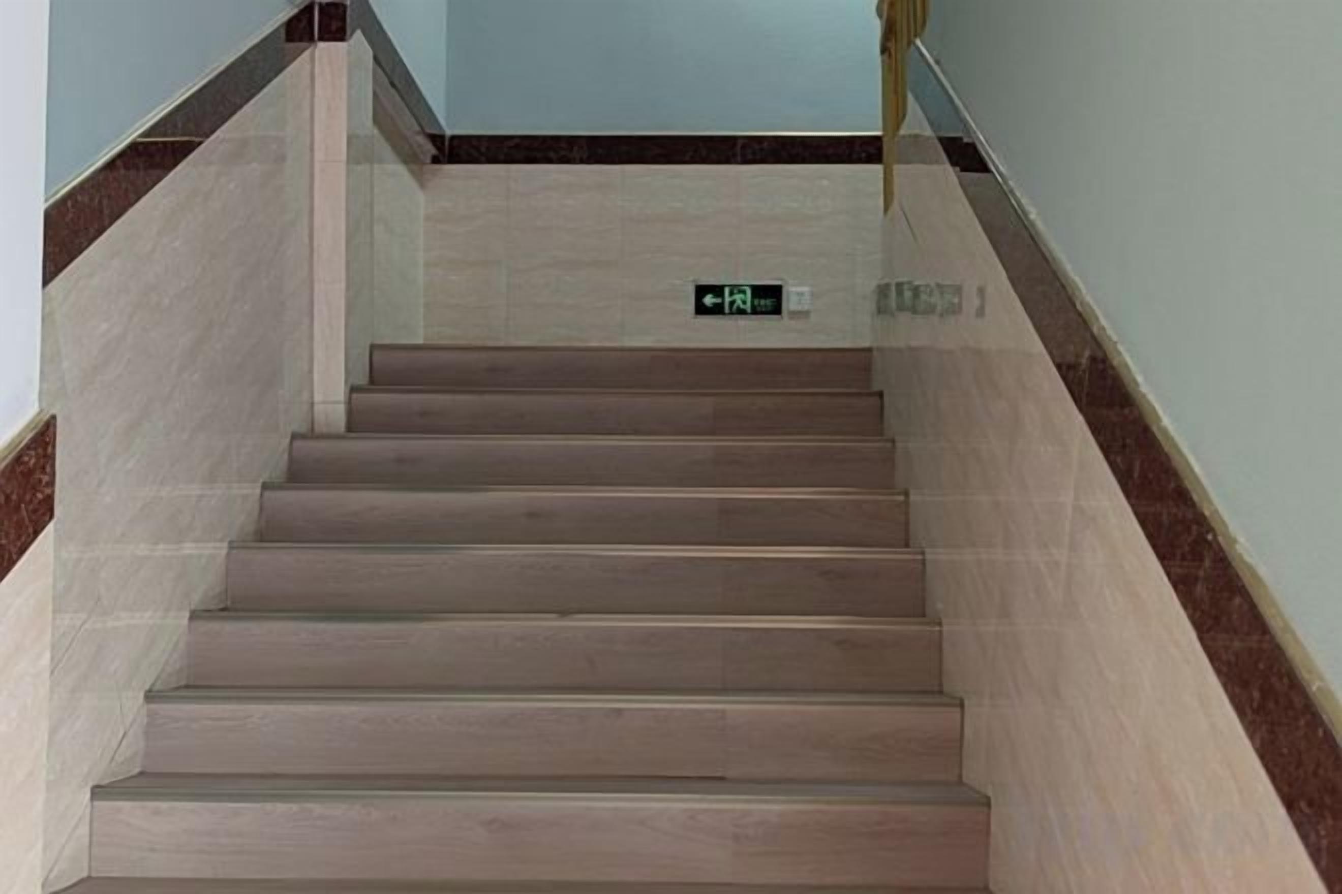 A staircase with a handrail and a sign indicating an exit.