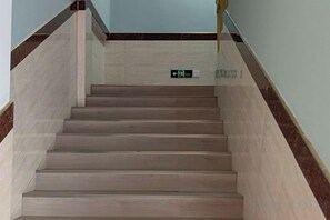 A staircase with a handrail and a sign indicating an exit. - Zhexin Business Hotel (Shanghai)