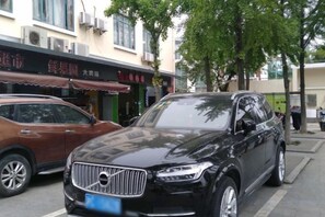 A black SUV parked on a city street with storefronts in the background. - Zhexin Business Hotel (Shanghai)