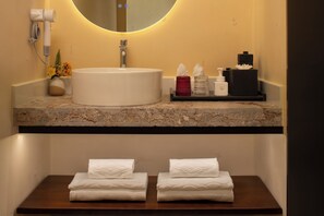 A bathroom with a round mirror, a white sink, and a wooden vanity with two folded towels. - Lanxiu Homestay (Lijiang)