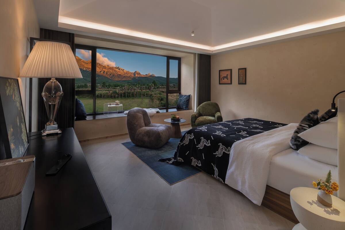 A modern bedroom with a large window, a bed, a desk, and a chair.
