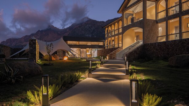 A modern building with a central courtyard, stone walls, and a mountain backdrop. - Lanxiu Homestay (Lijiang)
