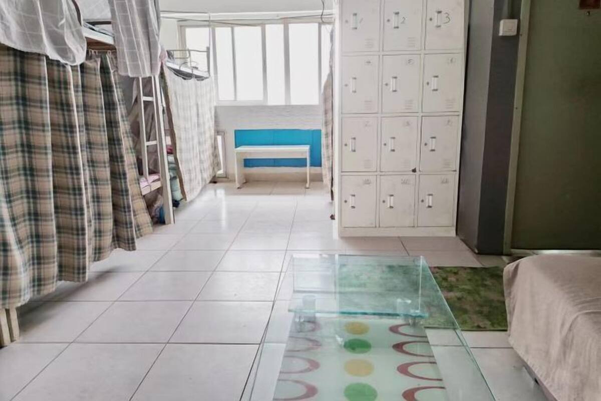A hotel room with a bed, a bench, a wardrobe, and a glass table with a colorful pattern.