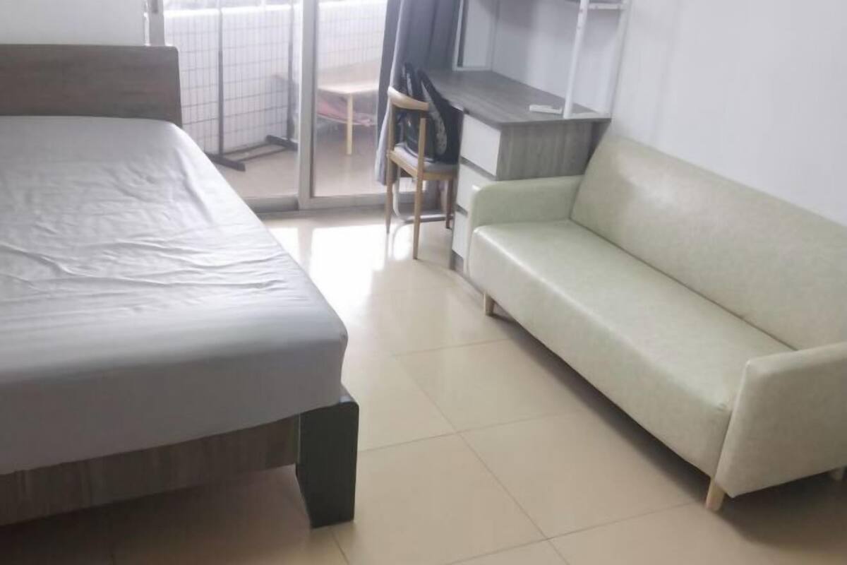 A room with a bed, a sofa, a desk, and a chair.