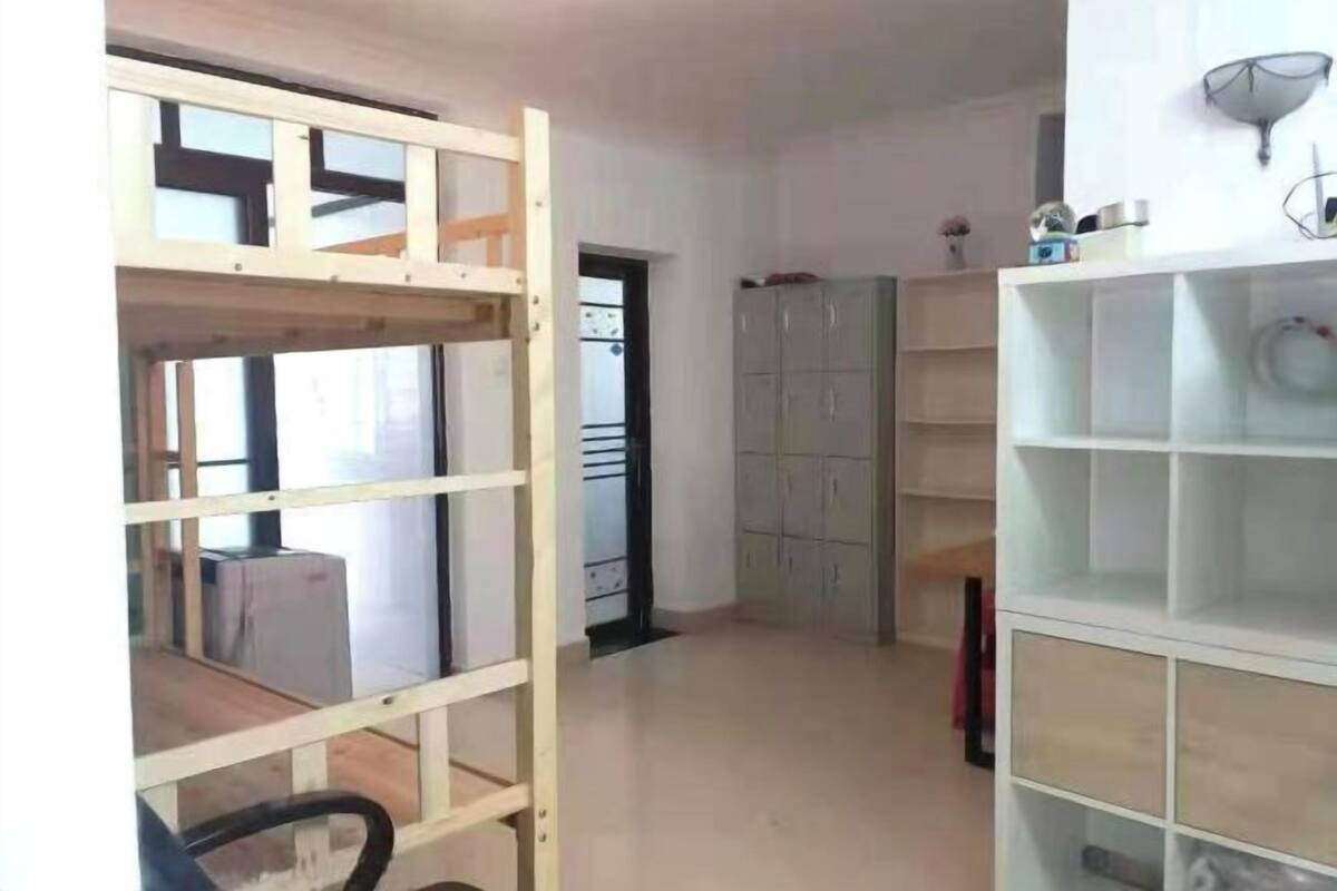 A room with a bunk bed, a wardrobe, and a shelving unit.