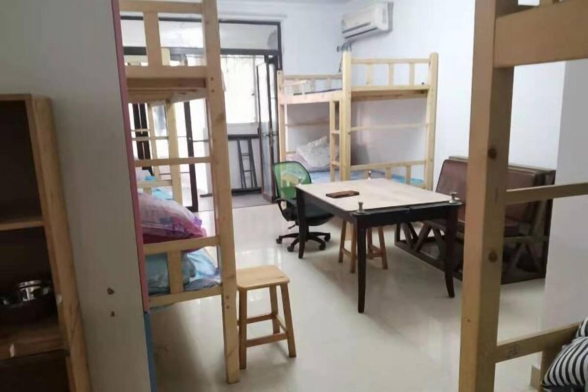 A room with bunk beds, a desk, a chair, and a small stool.