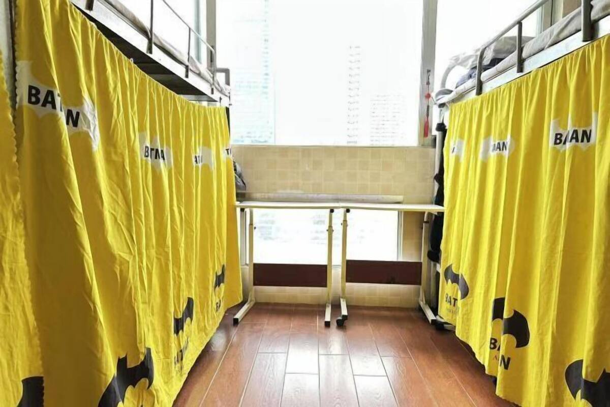 A room with yellow curtains, a bed, and a window with a view of buildings.