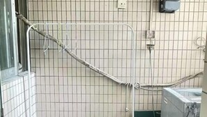 Pared de azulejos con un estante metálico y un enchufe.