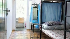 Una habitación tipo dormitorio con una cama litera, una mesita, una silla y una ventana con cortinas.